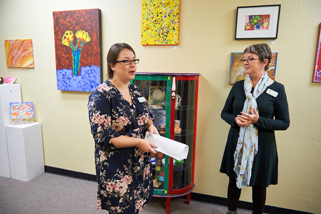 Angela Grech and Lisa Folsom-Ernst amid a display of artwork by clients.