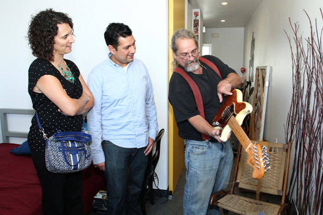 Resident Bill Fisher shows Dana Trujillo and Joey Aguilar how he restored a found guitar.
