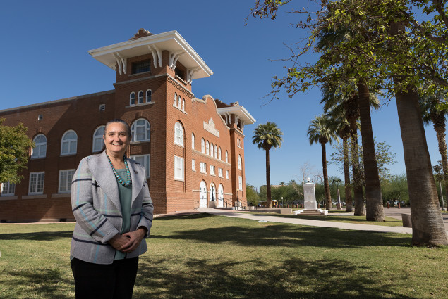 Dede Yazzie Devine, President and CEO of Native American Connections. In the background is the park's Memorial Hall, built in 1922 to commemorate the students from the school who died fighting for the United States in World War I.